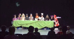 дзеці ў касцюмах за сталом на сцэне