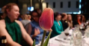 blomma framför människor som sitter vid ett festdukat bord