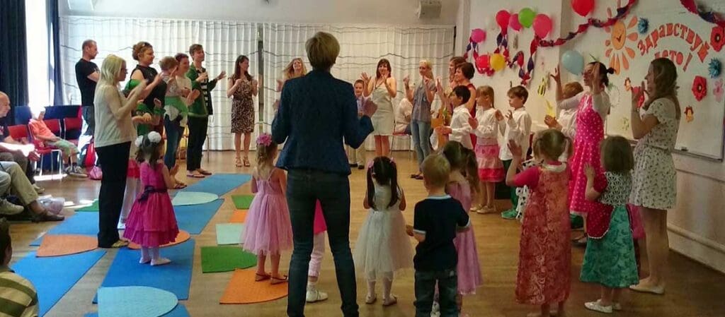 дети и взрослые танцуют хоровод в зале