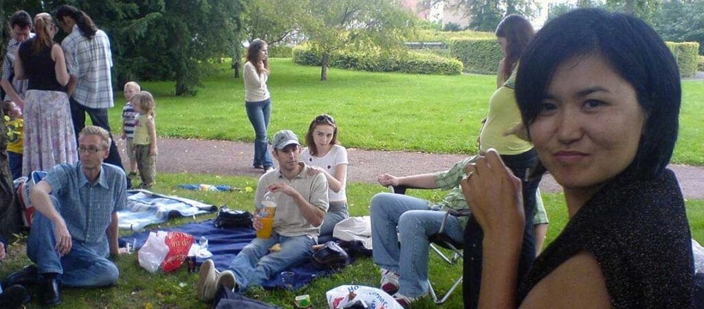 människor som sitter och står på en picknick i en park
