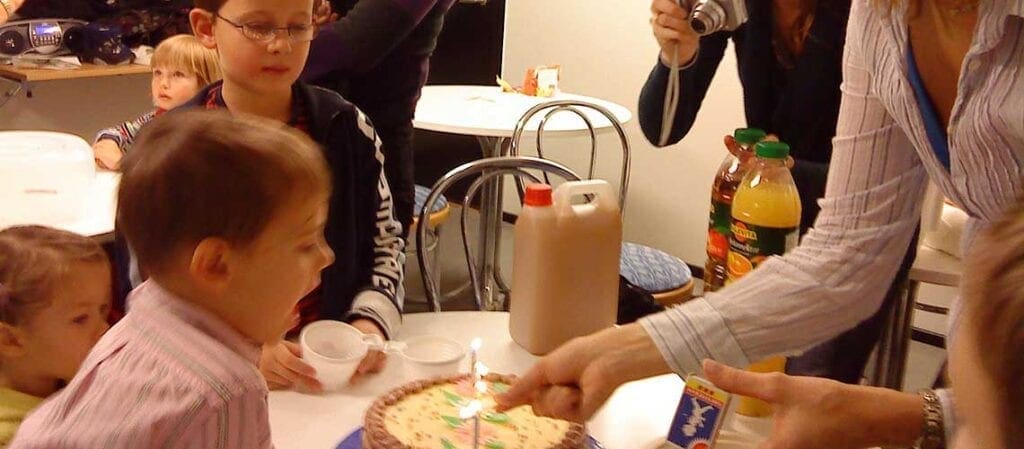 мальчик, выдувающий свечки на торте
