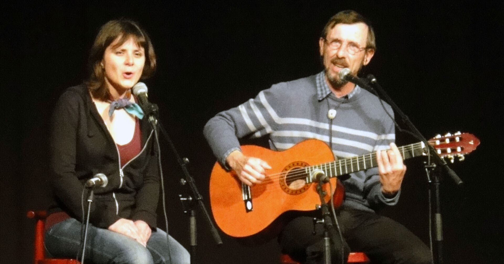 жінка сидить поруч із чоловіком з гітарою