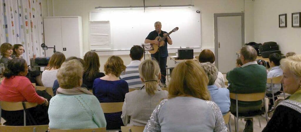 en man som sjunger och spelar gitarr inför publik
