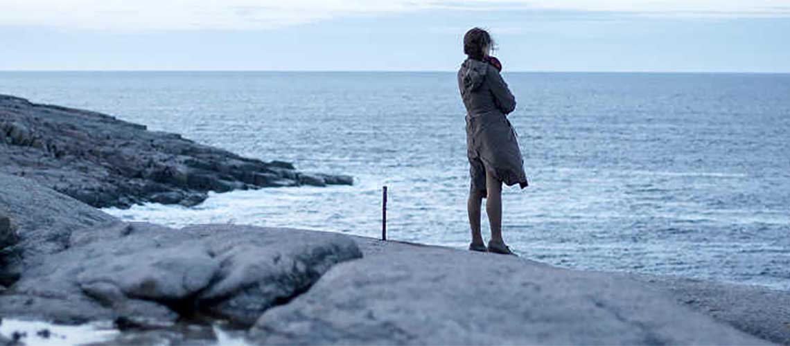 женщина, стоящая на скале, глядя на море