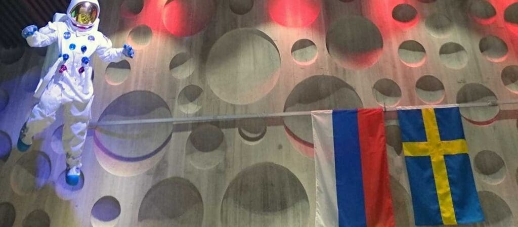 космонавт, висящий рядом с флагами России и Швеции