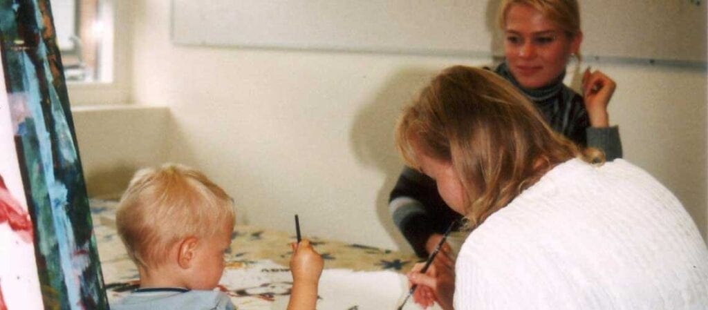 рисующий ребенок и двое взрослых