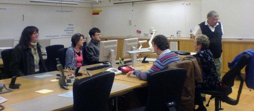 люди, сидящие за столом перед докладчиком