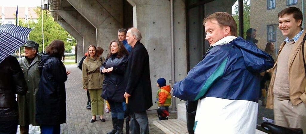 en grupp människor som står vid en betongbyggnad utomhus
