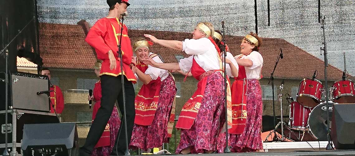 танцоры, выступающие на сцене в костюмах в русском стиле