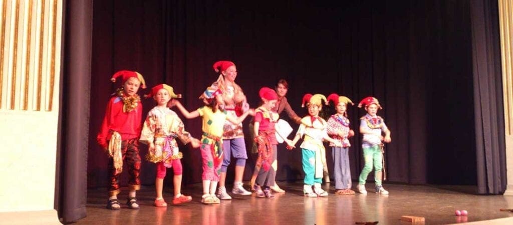 дети, танцующие на сцене в костюмах скоморох