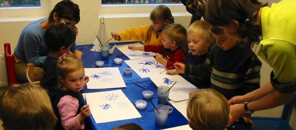 дети и взрослые за столом с рисунками
