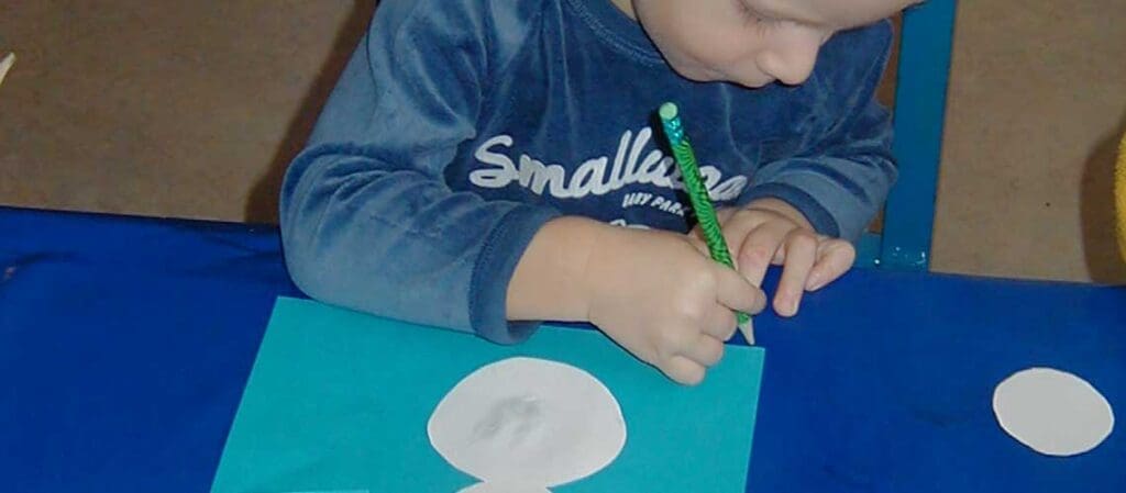 ребёнок, сидящий за столом, занимающаясь рукоделием