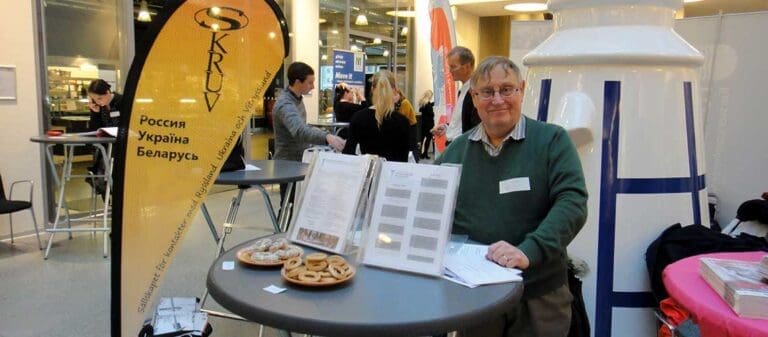 man stående vid högt runt bord och en flagga