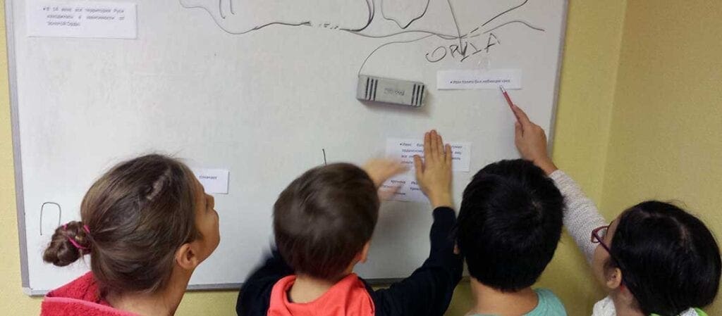 fyra barn som står framför en whiteboard vända mot den