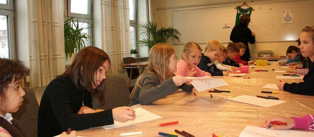 barn som sitter vid ett bord och ritar