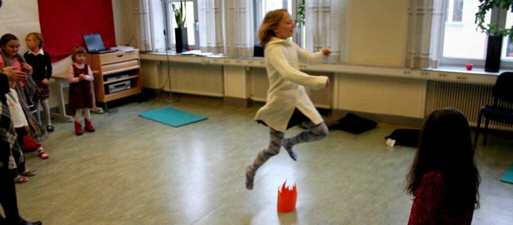 flicka som hoppar över eldslågor av papper i ett rum