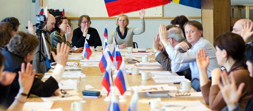 люди за столом, украшенном российскими флагами