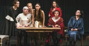 7 женщин, сидячих и стоящих за столом