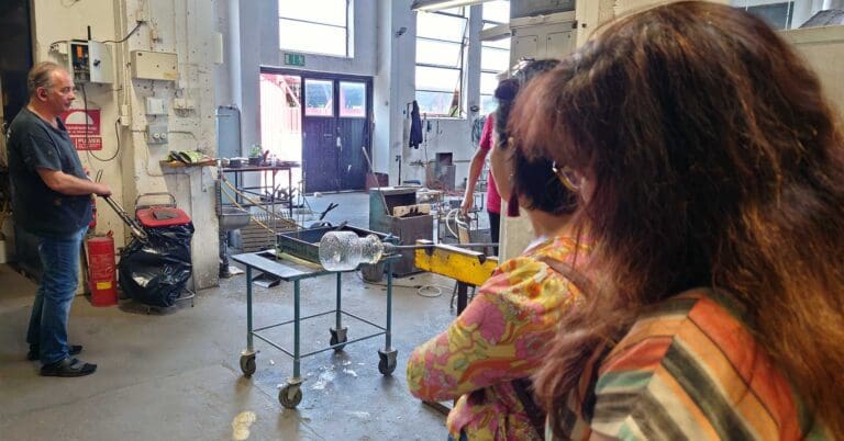 två kvinnor som tittar på arbete med glas i en verkstad