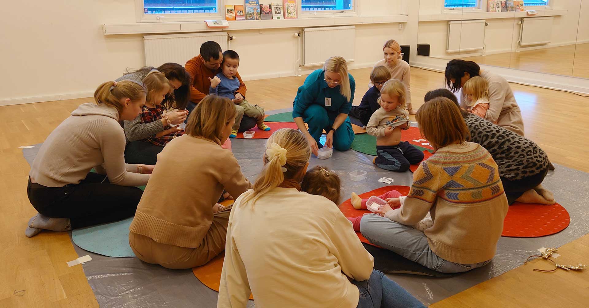 дети и взрослые, сидящие в кругу на полу