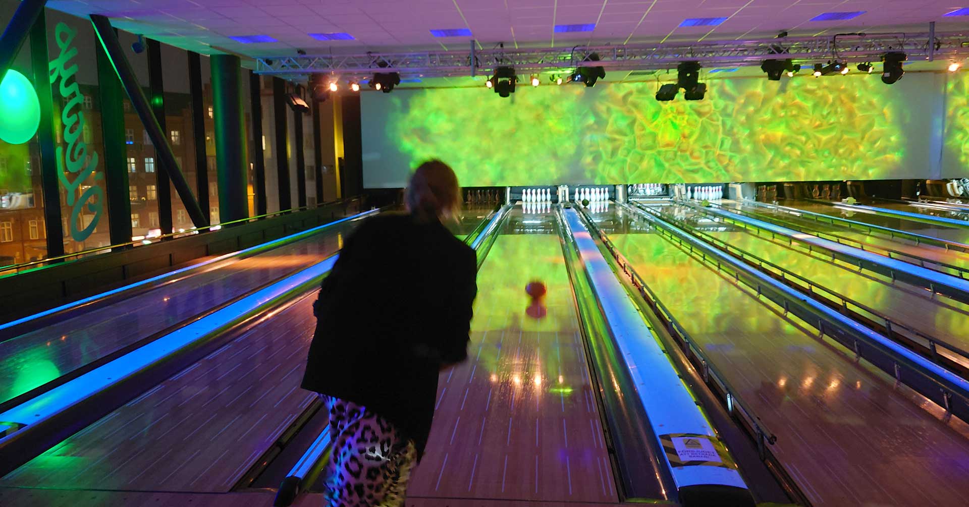 en kvinna som kastar ett klot längs en bowlingbana
