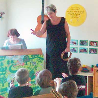 kvinna som står bredvid ett piano och talar till barn
