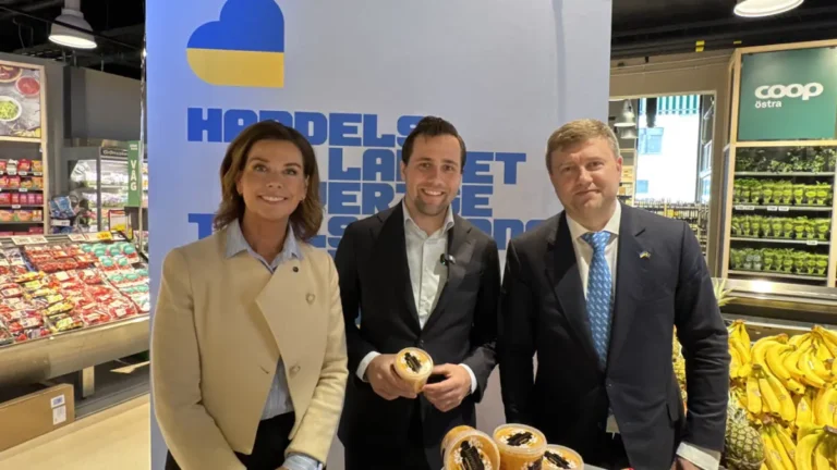 tre personer framför en rollup i en matbutik